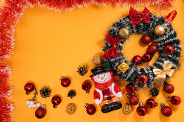 Holiday composition featuring a Christmas wreath, snowman, and vibrant decorations surrounded by tinsel, perfect for seasonal themes.