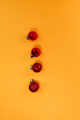 Minimalist arrangement of festive red baubles on a bright orange surface, highlighting a holiday theme.