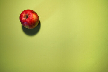 Minimalist close-up of one apple on a vibrant green surface, highlighting contrast and natural...