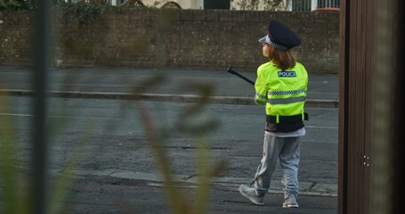 6-Year-Old Boy with Long Red Hair in Policeman Costume Holding a Bicycle Pump in His Hand Like a Lollipop and Directing Local Neighborhood Traffic 