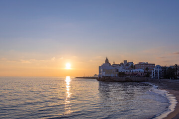 Fototapeta premium Beautiful sunset over the ocean with a small town in the background