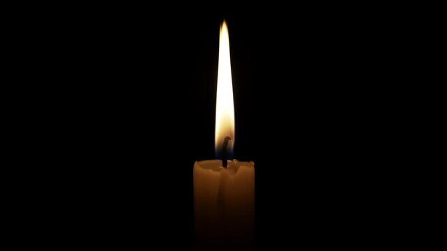 Single candle burning in the dark, providing a warm glow. The flame flickers gently, creating a peaceful and contemplative atmosphere