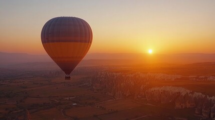A hot air balloon floats over a scenic landscape at sunset, creating a tranquil atmosphere.