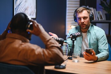 Man recording podcast using high tech microphones to interview guest, ensuring flawless video and...