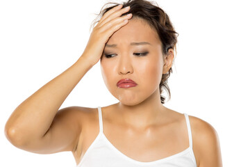 Asian woman suffering from stress or a headache grimacing in pain.