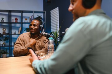 Podcasters enjoying happy conversations with online listeners in studio, covering wide range of...