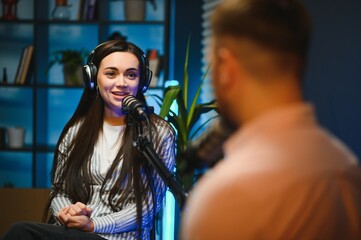 Female podcaster in headphones interviewing man guest using microphone, smiling, recording and...