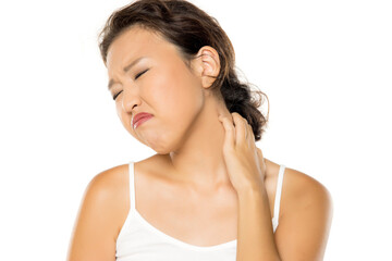 Asian woman with pain in the nech holding it with arm with painful expression on her face