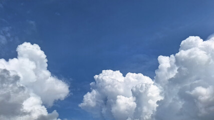 Clear blue sky with fluffy white clouds. The clouds look like scattered cotton, creating a peaceful and calm scenery with Blue sky background.