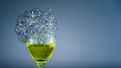 The photo shows soap bubbles floating in the air, creating a dynamic composition. Light through the bubbles creates reflections and a spectrum of colors. An elegant glass, space for text