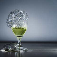 The photo shows soap bubbles floating in the air, creating a dynamic composition. Light through the bubbles creates reflections and a spectrum of colors. An elegant glass, space for text