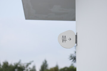 A sign showing the way to the restroom is installed on the wall. Modern restroom signage reflects minimalism.