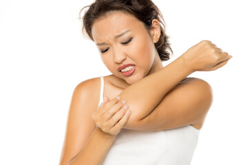 Asian woman with pain in the elbow, holding it with arm with painful expression on her face