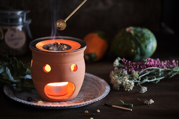 Placing various types of incense like frankincense and sandalwood with a spoon on an incense burner...
