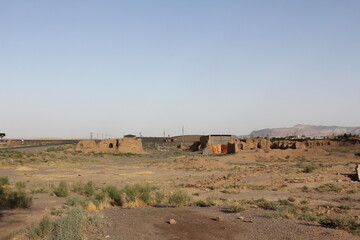 Ruined structures in a vast desert under a blue sky, highlighting abandoned architecture and the stark beauty of arid landscapes.