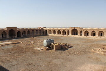 Desert courtyard with historic brick buildings, evoking a sense of isolation and traditional...