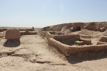 Desert excavation site with ancient stone foundations and pathways, showing the historical remnants...