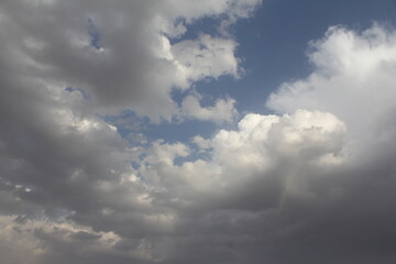 Dynamic sky with sunbeams and clouds over vast land, reflecting the diverse weather and natural beauty of the desert.