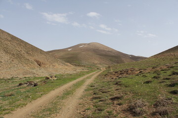 Winding mountain trail surrounded by green slopes and wild vegetation