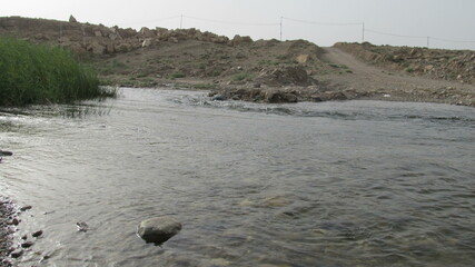 A tranquil river flows through grassy landscapes, reflecting sunlight and creating a peaceful scene in the heart of nature.