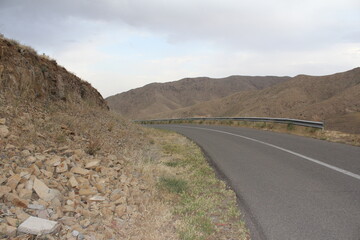 Winding road with mountains in the background, surrounded by greenery and a tranquil setting.