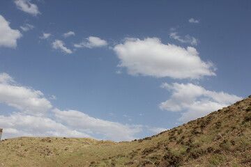 Rocky terrain with bright, white clouds against a clear sky, emphasizing the rugged, untouched landscape.