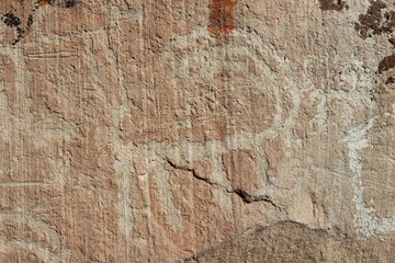 Close-up of engravings on a large stone in a desert area, emphasizing historical and cultural significance.