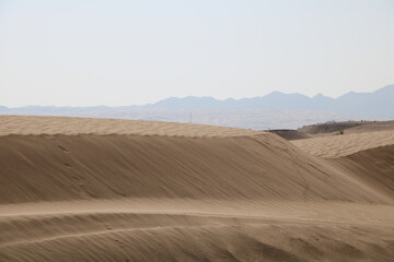Wavy sand dunes in the desert, creating a unique pattern and texture under the sunlight.