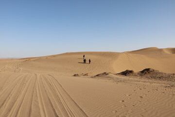 Two people on sand dunes, emphasizing the peacefulness and openness of the desert.