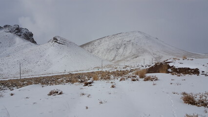 A wide, snowy plain surrounded by rugged mountains, depicting the vastness and beauty of winter...