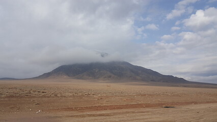 A distant view of a lone mountain under a cloudy sky, highlighting isolation and serenity.