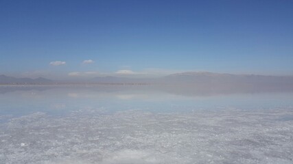 A tranquil view of a salt lake under a soft blue sky, capturing its serene beauty.