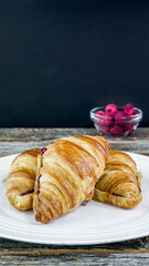 Three croissants filled with fruit preserves sit on a white plate, ready to be enjoyed