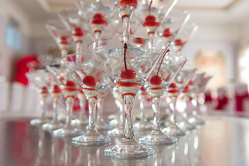 A pyramid of cocktail glasses with cherries. A pile of champagne glasses at a banquet.