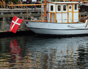 Danish boat and the white and red flag of Denmark reflected in the water
