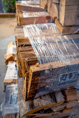 Bundles of kiln dried firewood for home use wrapped in plastic and stacked in a display for sale outside of store.