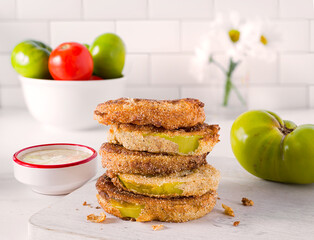 US southern food of fried green tomatoes in a kitchen scene with dipping sauce and fresh tomatoes on the side
