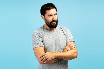 Skeptical man crossing arms on blue background