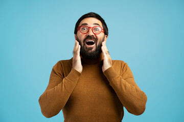 Surprised man touching face with open mouth and red glasses