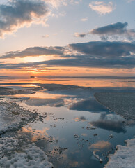  Winter landscape. The surface of the ice is bound by ice, with a perfectly smooth, mirror-like appearance. Sunset in winter over the lake. 
