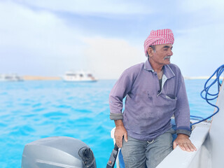 Old Sailor in the Sea Riding and Sailing with his Boat An old sailor with a white with a white mustache who is wearing a Bedouin Scarf on his head