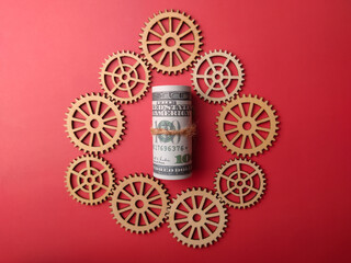 Top view banknotes and wooden gear on a red background. Business concept