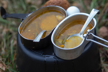 Cooked soup in a camping pot. Snack in the forest: soup, chicken egg and a piece of bread