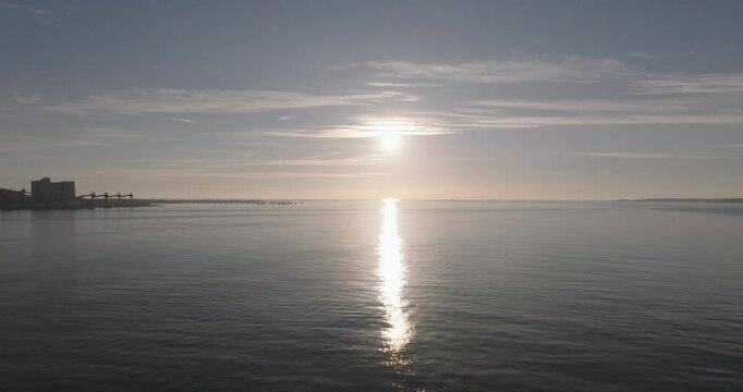 Aerial drone shot flying towards the Atlantic Ocean and horizon at sunset from Lisbon, Portugal, Europe. Drone flying towards the Forte do Bugio lighthouse during golden hour. Shot in ProRes 422 HQ