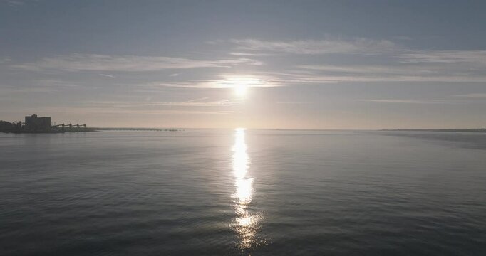 Aerial drone shot flying towards the Atlantic Ocean and horizon at sunset from Lisbon, Portugal, Europe. Drone flying towards the Forte do Bugio lighthouse during golden hour. Shot in ProRes 422 HQ