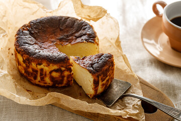 Traditional Basque cheesecake with cut portion on baking paper, close up view