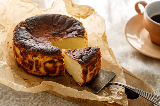 Traditional Basque cheesecake with cut portion on baking paper, close up view
