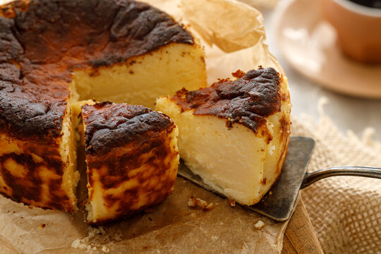 Traditional Basque cheesecake with cut portions on baking paper, close up view