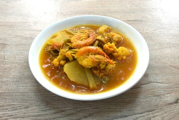 boiled shrimp and mixed vegetable in spicy and sour orange curry soup on plate 
