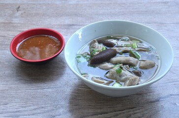 boiled slice pork stomuch and bone soup in bowl dipping spicy sauce cup on table 